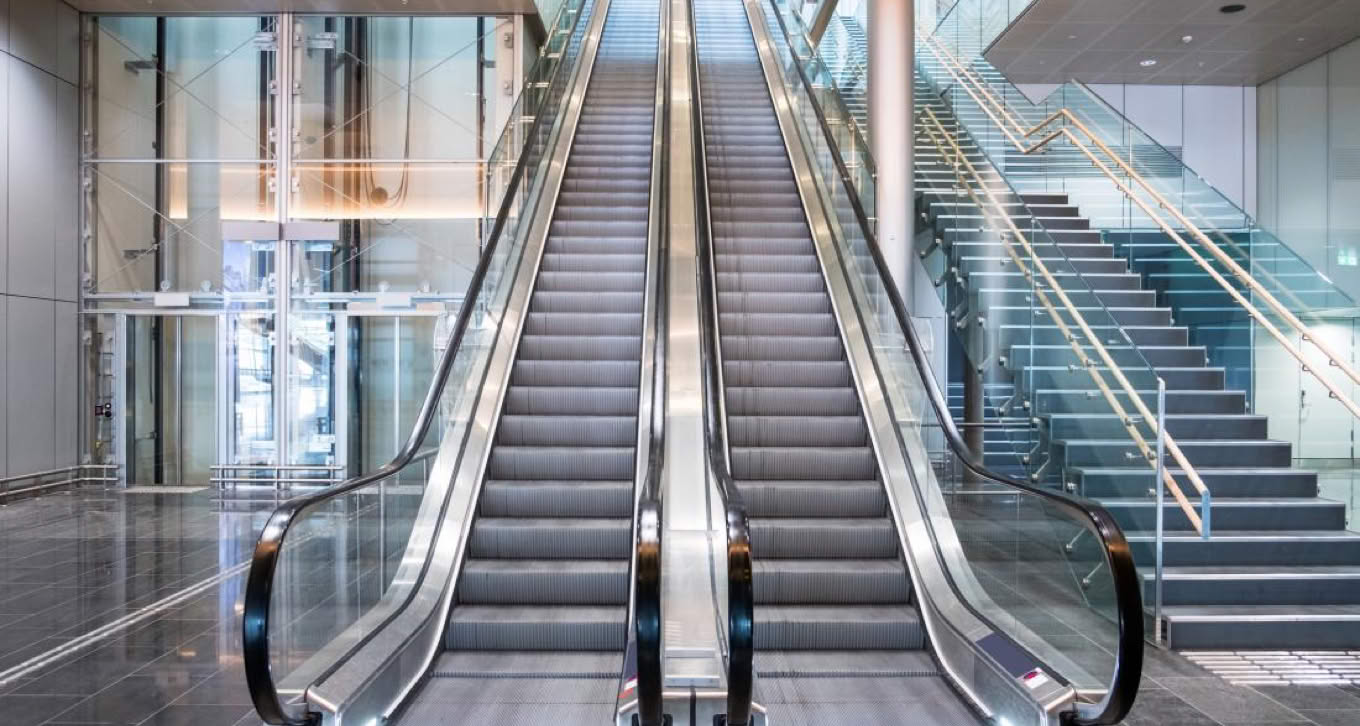 Two parallel escalators in a modern building interior.