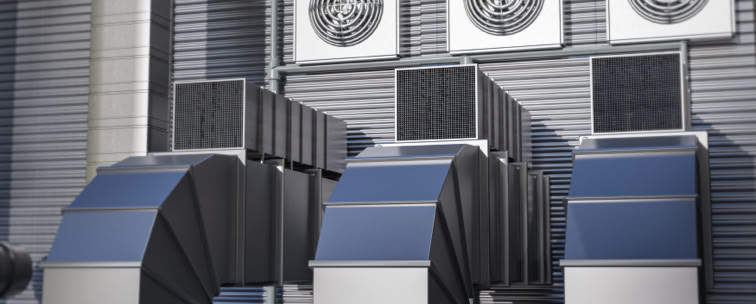 Industrial ventilation system with large ducts and fans on a building exterior.