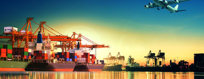 Cargo ship at a port with cranes and an airplane flying overhead at sunset.