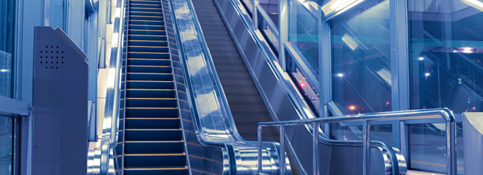 Escalator in a modern, well-lit indoor setting with blue tones.
