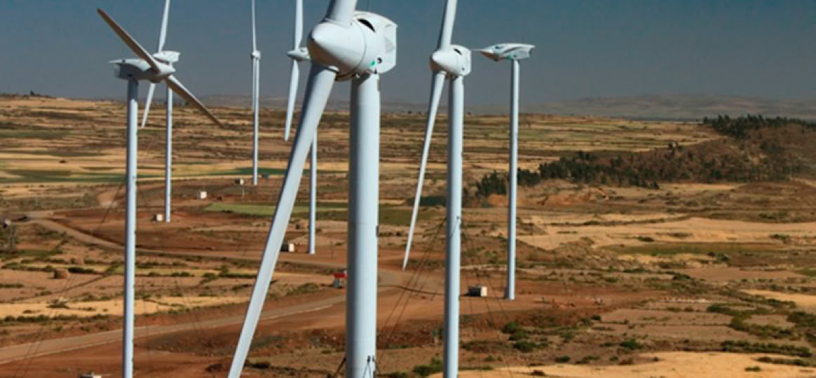 Wind turbines on a dry landscape under a clear blue sky.
