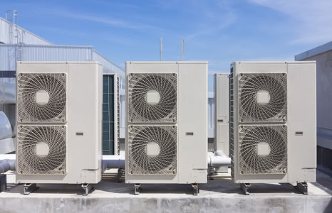 Three large industrial air conditioning units on a rooftop.